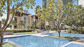 A modern pool area with tiled flooring, surrounded by well-maintained grass and trees. - Silkhaus 3BR Maid Room in Marina Heights Tower (Abu Dhabi)