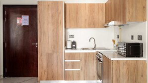 A modern kitchen with wooden cabinets, a microwave, a kettle, and a sink. - Silkhaus 1bdr Prime Location in Maryah Island (Abu Dhabi)