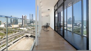 Ein moderner Balkon mit Stadtblick, ausgestattet mit Glasgeländer, einer Sitzecke und einem Holzboden.