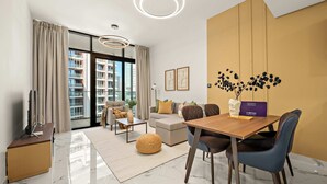 Ein modernes Wohnzimmer mit einem Holzesstisch, blauen Stühlen, einer Couch und einem großen Fenster mit Vorhängen.