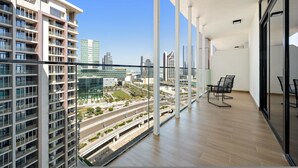 Eine hohe Apartmentwohnung mit Balkon, großen Fenstern und Blick auf die Skyline.