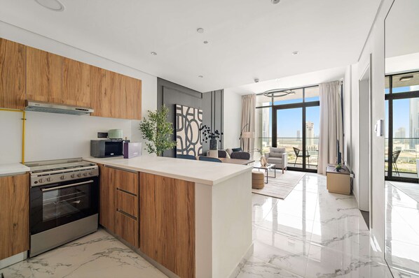 A modern kitchen with a built-in stove, microwave, and wooden cabinets. - Silkhaus New 1bdr Living in Maryah Island (Abu Dhabi)