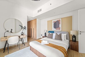 A modern hotel room with a bed, a desk, a chair, a round mirror, and a painting on the wall. - Silkhaus New 1bdr Living in Maryah Island (Abu Dhabi)
