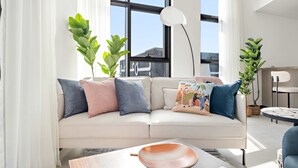 A modern living room with a beige sofa, decorative pillows, a coffee table, and potted plants. - Silkhaus Elite 1bdr Business Bay High Floor (Dubai)