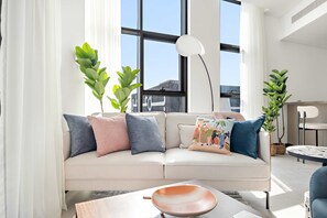 A modern living room with a beige sofa, decorative pillows, a coffee table, and potted plants. - Silkhaus Elite 1bdr Business Bay High Floor (Dubai)