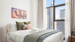 A modern hotel room with a large bed, a city view, and a colorful painting on the wall. - Silkhaus Elite 1bdr Business Bay High Floor (Dubai)
