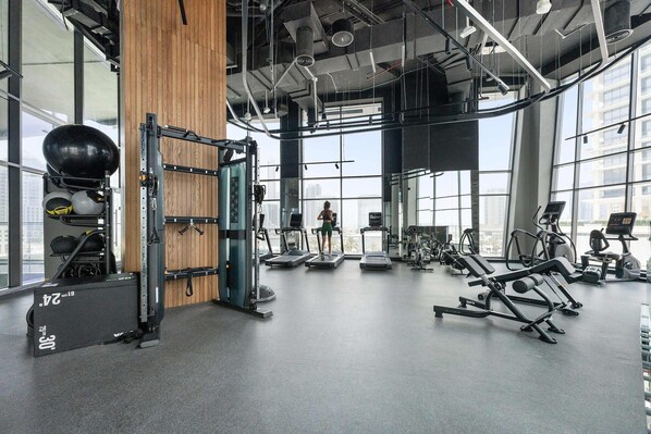 A gym with cardio machines, weightlifting equipment, and a large mirror. - Silkhaus Elite 1bdr Business Bay High Floor (Dubai)