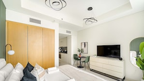 A modern hotel room with a large bed, a TV, a dining area, and a wooden wardrobe. - Silkhaus Cozy Studio High Floor Business Bay (Dubai)