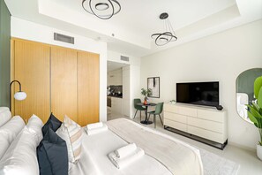 A modern hotel room with a large bed, a TV, a dining area, and a wooden wardrobe. - Silkhaus Cozy Studio High Floor Business Bay (Dubai)