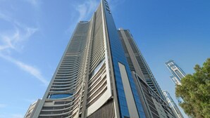 A tall, modern skyscraper with a curved facade and multiple balconies. - Silkhaus Cozy Studio High Floor Business Bay (Dubai)