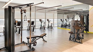 A gym with various exercise equipment, large windows, and a view of the city. - Silkhaus Cozy Studio High Floor Business Bay (Dubai)