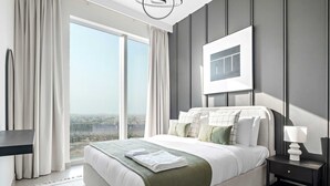 A modern bedroom with a large bed, a nightstand, a lamp, and a view of the city through a large window. - Silkhaus Modern 1 BDR Forte Tower Downtown (Dubai)
