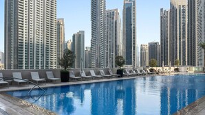 A swimming pool with lounge chairs and a view of high-rise buildings. - Silkhaus Modern 1 BDR Forte Tower Downtown (Dubai)