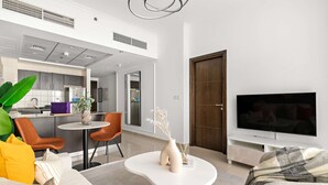 A modern living room with a sofa, coffee table, and TV. A kitchen is visible in the background. - Silkhaus Modern 1BR Dubai Marina Bay Central (Dubai)