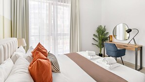 A hotel room with a bed, a desk, a chair, a mirror, a lamp, and a potted plant. - Silkhaus Modern 1BR Dubai Marina Bay Central (Dubai)