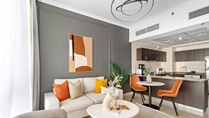 A modern living room with a sofa, coffee table, and a dining area with chairs. - Silkhaus Modern 1BR Dubai Marina Bay Central (Dubai)