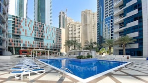A pool area with lounge chairs and a tiled floor, surrounded by high-rise buildings. - Silkhaus Modern 1BR Dubai Marina Bay Central (Dubai)