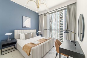 A modern bedroom with a bed, bedside tables, a desk, and a large window. - Silkhaus Urban Chic 1bdr Heart of Downtown (Dubai)