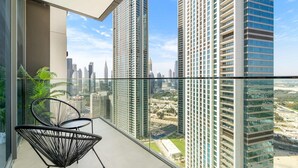 A high-rise apartment with a balcony featuring a glass railing, two black wireframe chairs, and a view of surrounding skyscrapers. - Silkhaus Urban Chic 1bdr Heart of Downtown (Dubai)