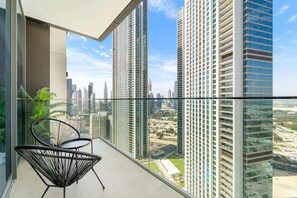 A high-rise apartment with a balcony featuring a glass railing, two black wireframe chairs, and a view of surrounding skyscrapers. - Silkhaus Urban Chic 1bdr Heart of Downtown (Dubai)