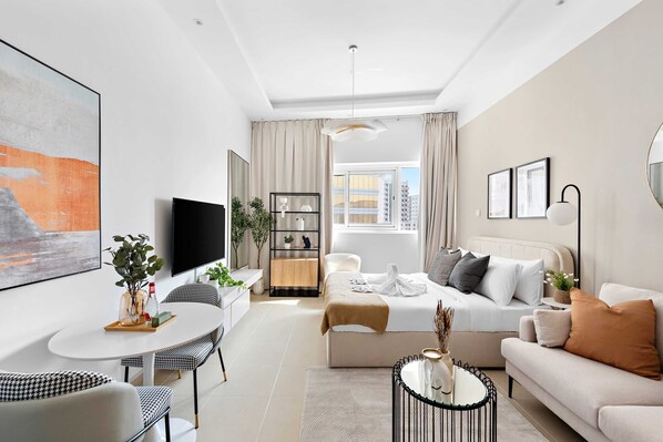 A modern, well-lit living room with a sofa, coffee table, and dining area. - Silkhaus New Luxurious Studio Near Silicon Mall (Dubai)