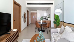 A modern living room with a flat-screen TV, wooden entertainment unit, and a round coffee table with a decorative plant. - Silkhaus Elite 1bdr in JVC Summer Promotion (Dubai)