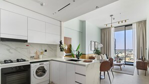 A modern kitchen with built-in appliances, a dining area with a view, and a large window. - Silkhaus Elite 1bdr in JVC Summer Promotion (Dubai)