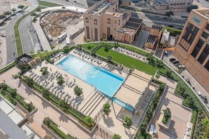 An aerial view of a hotel with a swimming pool, surrounded by a landscaped garden and a parking area. - Silkhaus Stylish 1BR Pool Gym Burj Crown (Dubai)