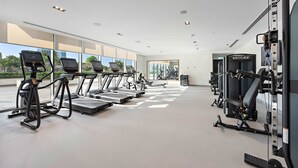 Ein modernes Fitnessstudio mit Laufbändern, Kraftgeräten und großen Fenstern mit Blick ins Freie.