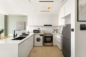 Eine moderne Küche mit Einbauwaschmaschine, Backofen und Kühlschrank.