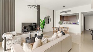 Uma sala de estar moderna com um sofá, um espaço de jantar e uma cozinha ao fundo.