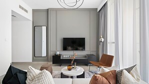 Ein modernes Wohnzimmer mit einer Couch, einem Couchtisch und einem Flachbildfernseher auf einem Schrank.