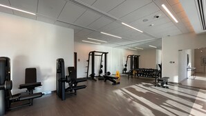 Ein Fitnessraum mit unterschiedlichen Trainingsgeräten, einem Spiegel und einem klaren, modernen Design.