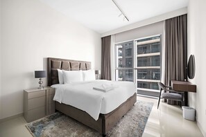 Ein modernes Hotelzimmer mit einem großen Bett, Nachttischen, einem Schreibtisch und Blick auf die Stadt durch große Fenster.