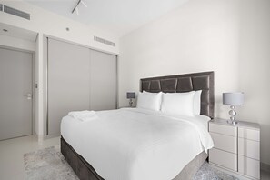 Ein modernes Hotelzimmer mit einem großen Bett, einem Nachttisch mit Lampe und einem Kleiderschrank.