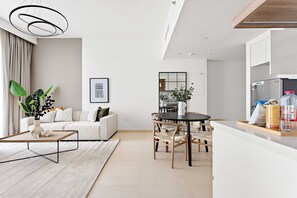 A modern living room with a sofa, coffee table, and dining area. - Silkhaus Stylish 1BR Near Burj Khalifa Balcony (Dubai)