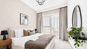 A modern hotel room with a large bed, a bedside table with a lamp, a framed picture on the wall, and a large mirror. - Silkhaus Stylish 1BR Near Burj Khalifa Balcony (Dubai)
