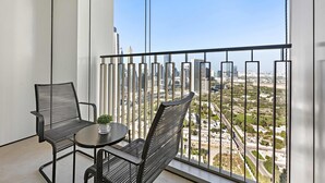 A balcony with two chairs and a small table, overlooking a cityscape with modern buildings and a clear sky. - Silkhaus Stylish 1BR Near Burj Khalifa Balcony (Dubai)