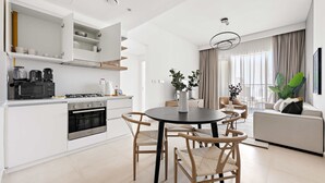 A modern kitchen with white cabinetry, a built-in oven, and a dining area with a round table and chairs. - Silkhaus Stylish 1BR Near Burj Khalifa Balcony (Dubai)