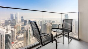 Ein Balkon mit zwei Stühlen und einem Tisch, der Blick auf die Stadt bietet.