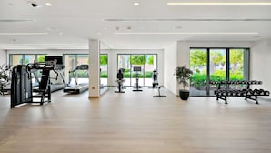 Ein modernes Fitnessstudio mit Cardiogeräten, Gewichtsbänken und einem großen Fenster, das für natürliches Licht sorgt.