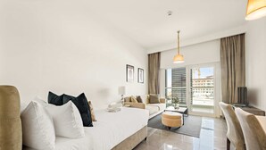 A modern hotel room with a large bed, a sofa, a coffee table, and a TV. - Silkhaus Studio Masdar City Leonardo Residence (Abu Dhabi)