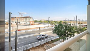 A view of a road with a car, a construction site, and a building under construction. - Silkhaus Studio Masdar City Leonardo Residence (Abu Dhabi)
