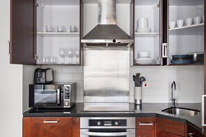 Une cuisine moderne dotée d’appareils électroménagers en acier inoxydable, de meubles en bois et d’un four encastré.