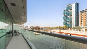 A modern building with a glass facade overlooking a body of water, with a clear view of the water and distant buildings. - Silkhaus Chic 1bdr in Al Bandar Al Naseem A (Abu Dhabi)