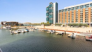 A marina with boats docked, a modern hotel building, and a distinctive architectural structure in the background. - Silkhaus Chic 1bdr in Al Bandar Al Naseem A (Abu Dhabi)