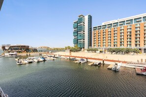 A marina with boats docked, a modern hotel building, and a distinctive architectural structure in the background. - Silkhaus Chic 1bdr in Al Bandar Al Naseem A (Abu Dhabi)
