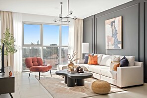 A modern living room with a large window, a white sofa, a red armchair, and a black coffee table. - Silkhaus Canal View 1BR Apartment In Reem Island (Abu Dhabi)
