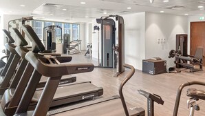 Un gimnasio moderno con cintas de correr, máquinas de pesas y un espejo.