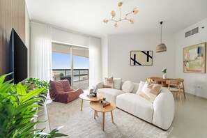 A modern living room with a sofa, coffee table, and a dining area. - Silkhaus Sea View 1BR With Free Mamsha Beach Access Saadiyat (Abu Dhabi)